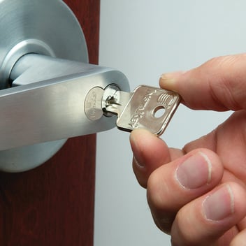 hand inserting a key into a door lock