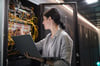 How Data Centers Employ Key Control: female IT employee looks at data center rack network of cables
