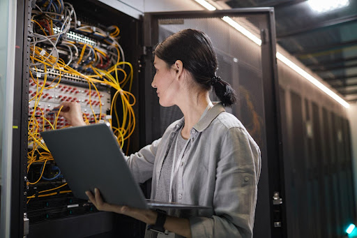 How Data Centers Employ Key Control: female IT employee looks at data center rack network of cables